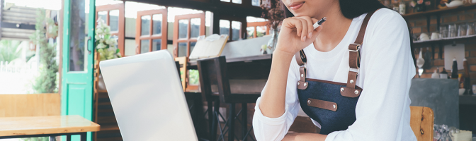 Female owner of small business cafe working on computer