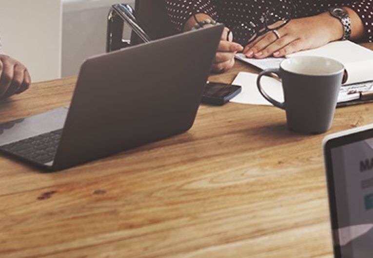 Business professionals working at table with laptops screen showing "Marketing Strategy"