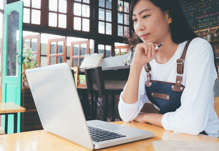 Female owner of small business cafe working on computer