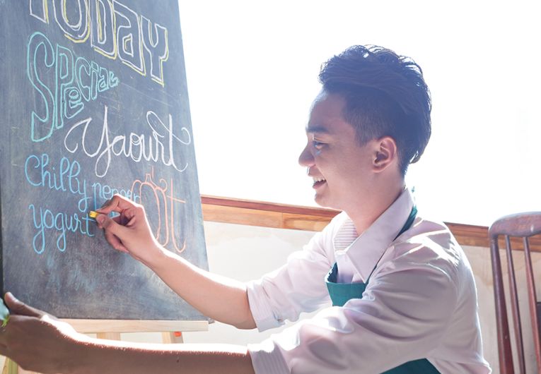 Cafe owner writing special menu on the chalkboard