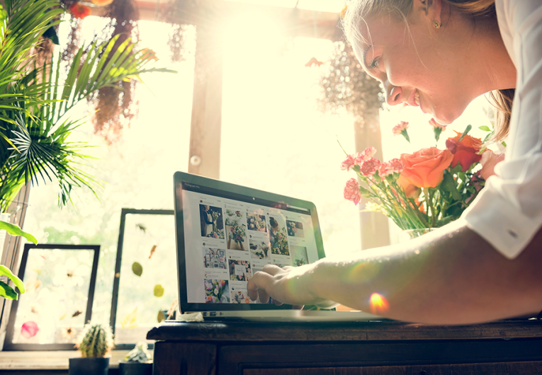 Female flower shop owner working on laptop promoting business on social media