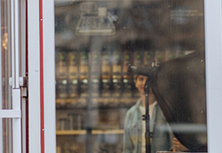 Female Entrepreneur stands by the door of her coffee shop.