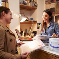 Two women talking sitting a desk.